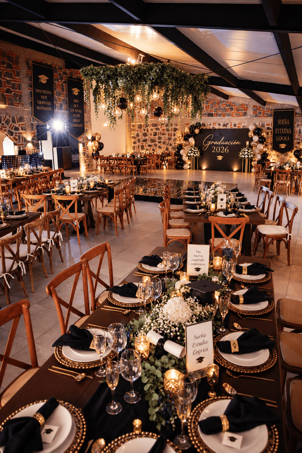 Salón ambientado para graduación con mesas de madera, viñetas doradas, globos y panel 'Graduación 2026'