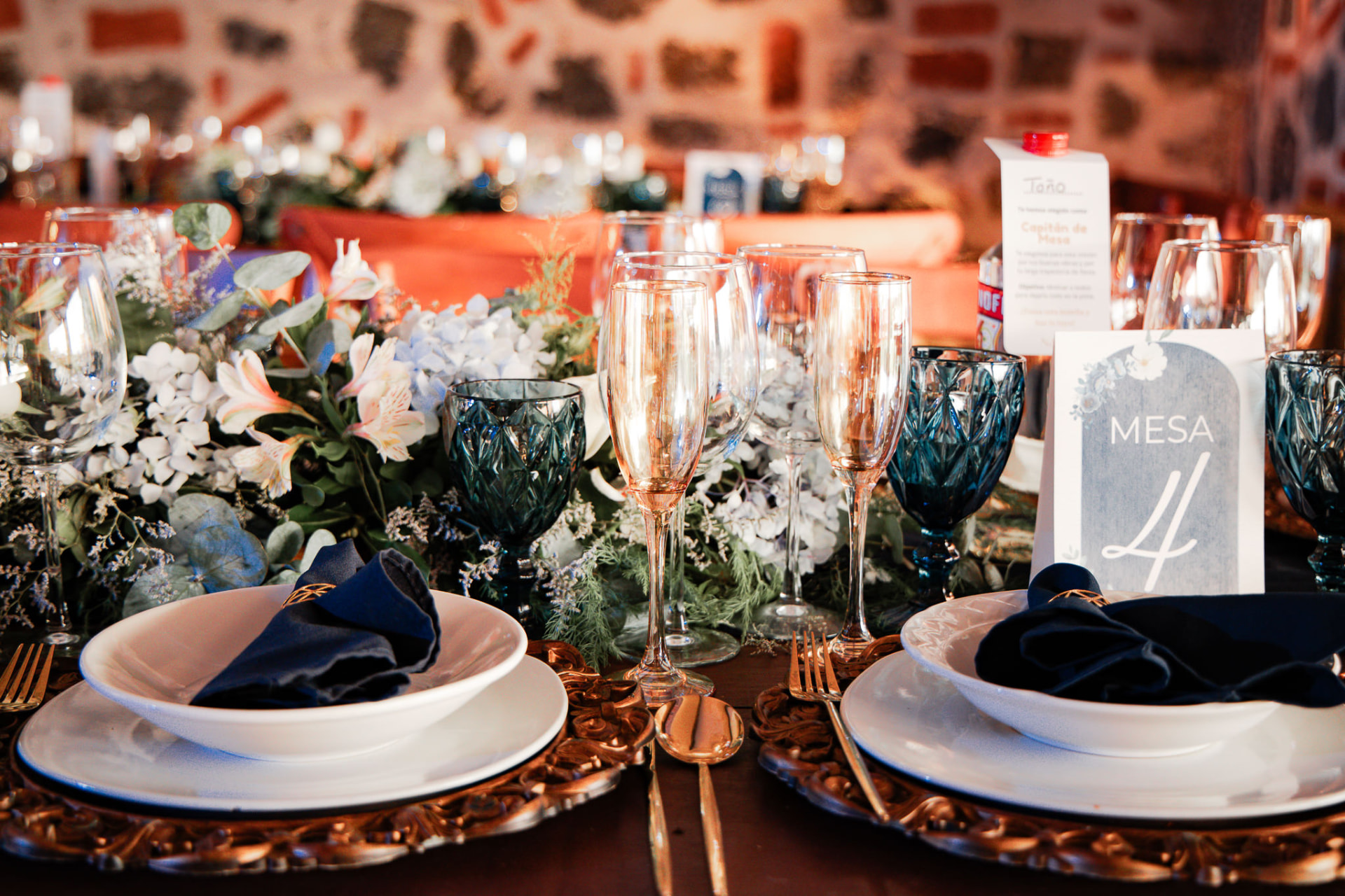 Mesa elegante ambientada con flores, copas y vajilla azul para una celebración