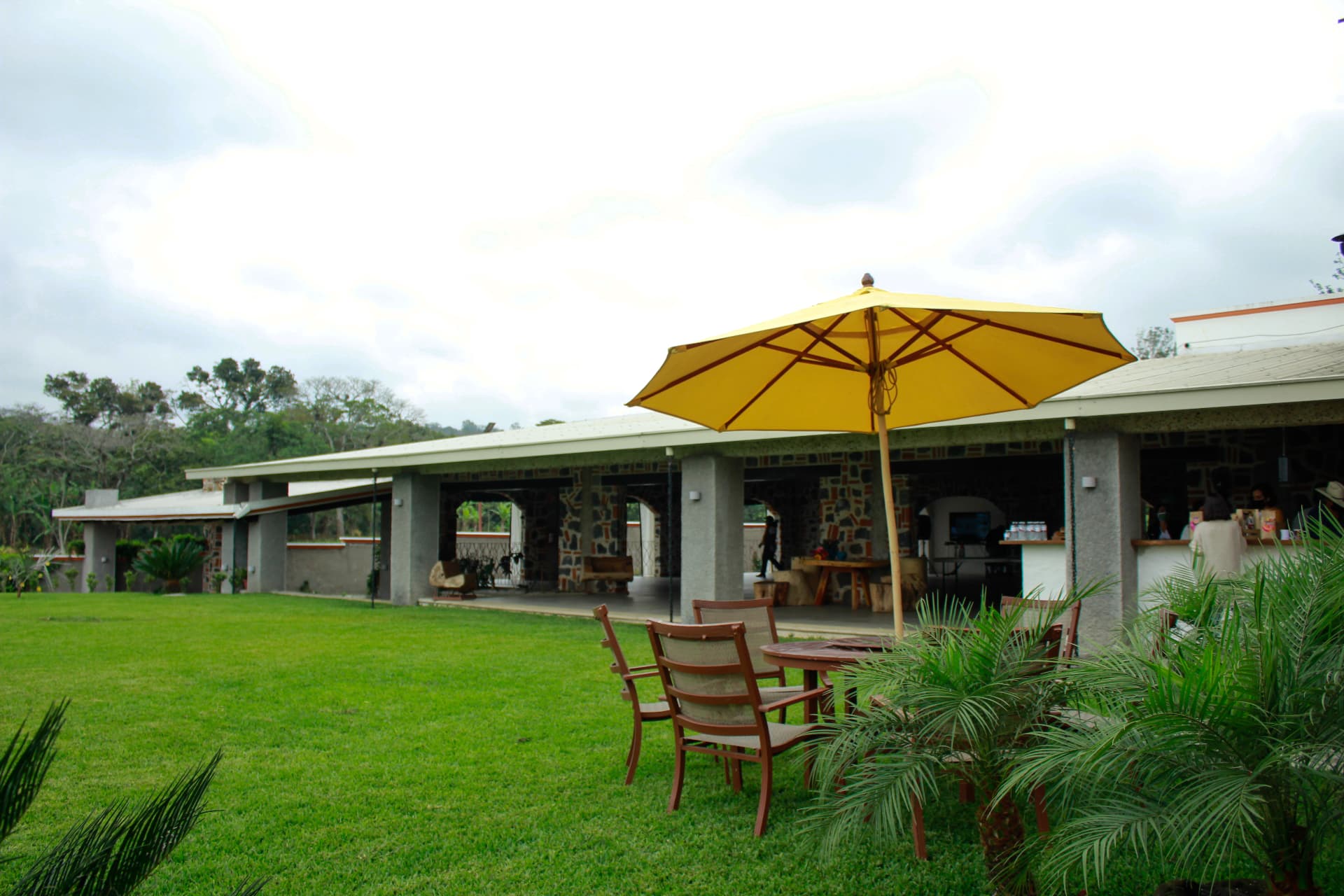 Jardín verde con sombrilla y terraza junto a la arquitectura de Quinta Los Mulatos