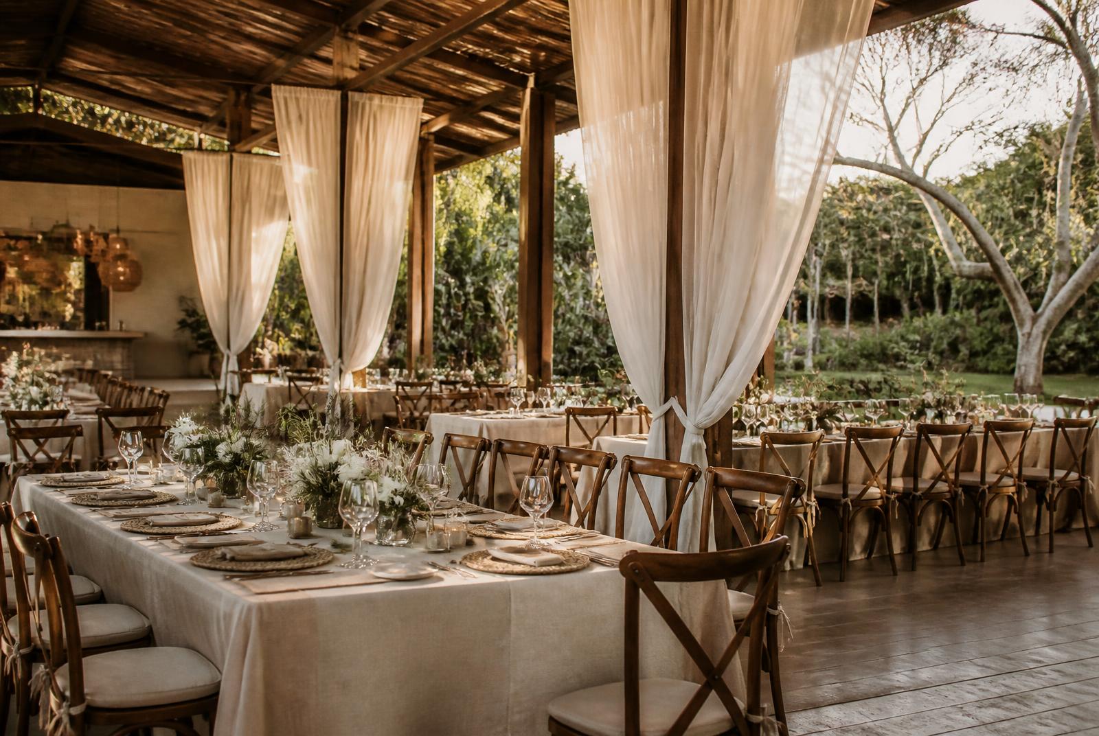 Salón de eventos con mesas largas y luz cálida